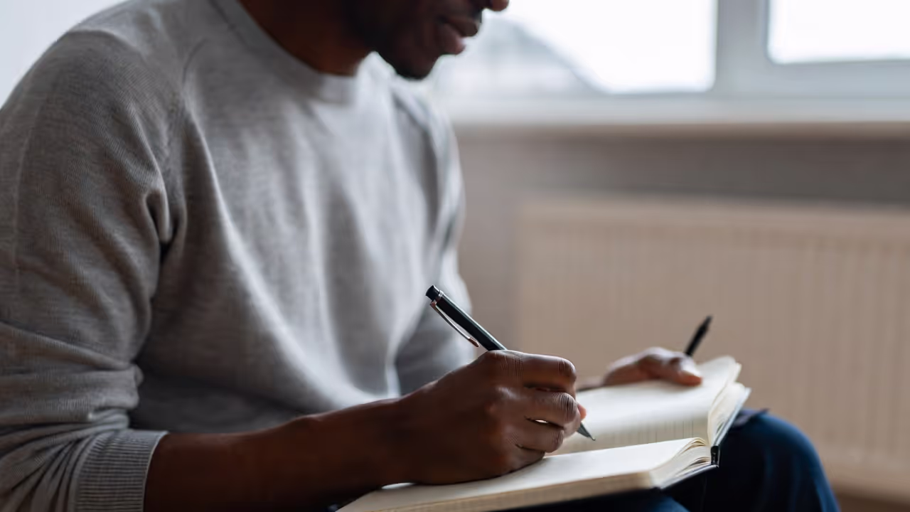 Adult journaling indoors with calmer, more focused expression